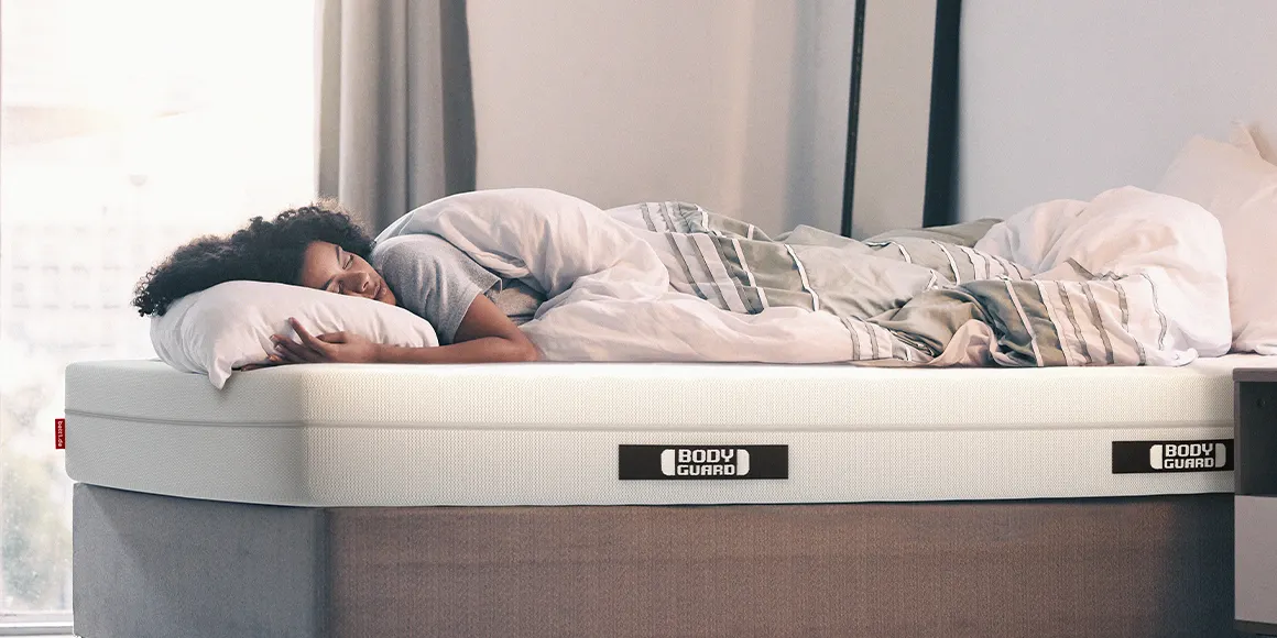 Photo: A person lies covered under a duvet in 155x220 bed linen on a BODYGUARD mattress
